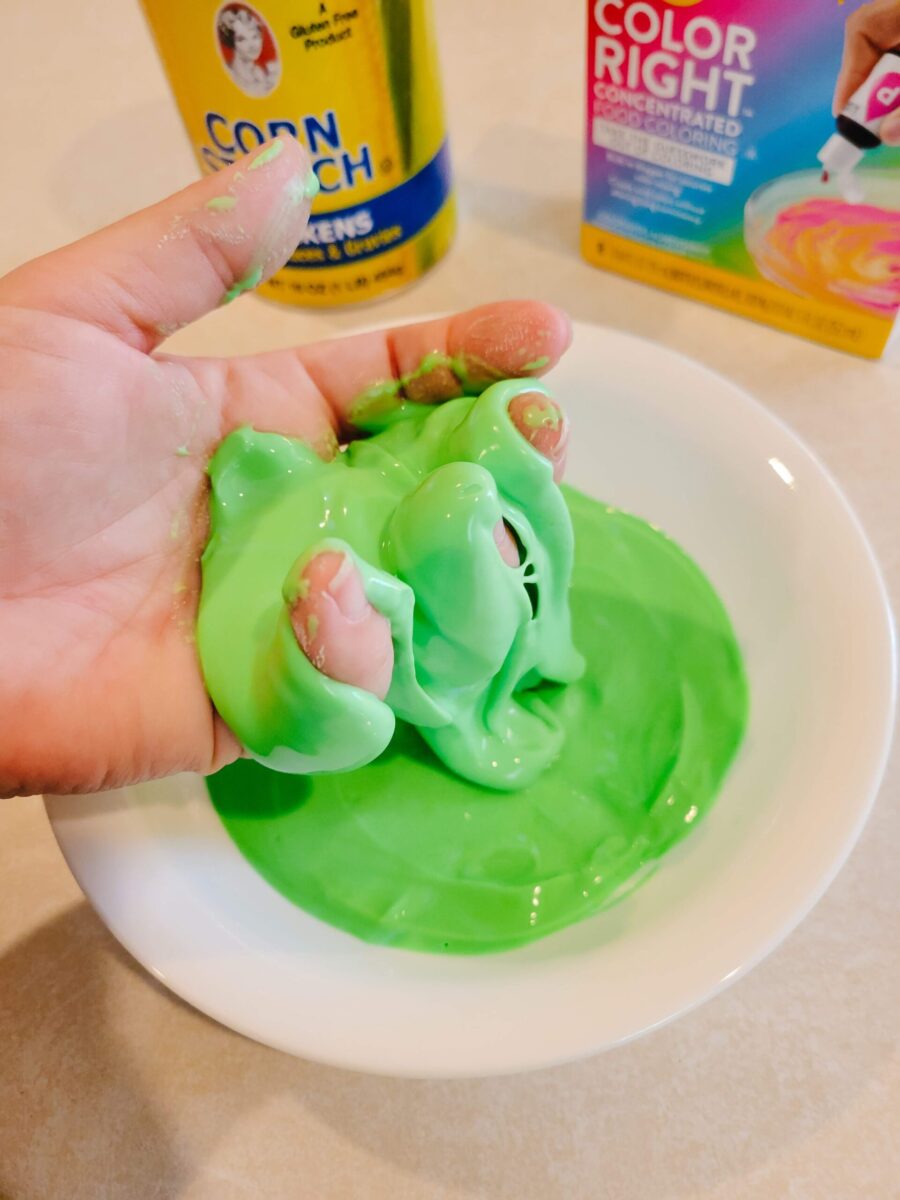 Hand with oobleck oozing out and supplies in background