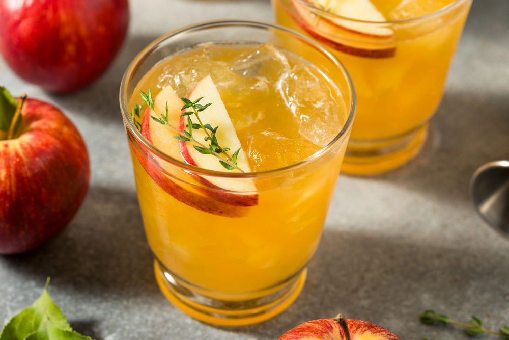 a glass of caramel apple punch with apple slice and thyme