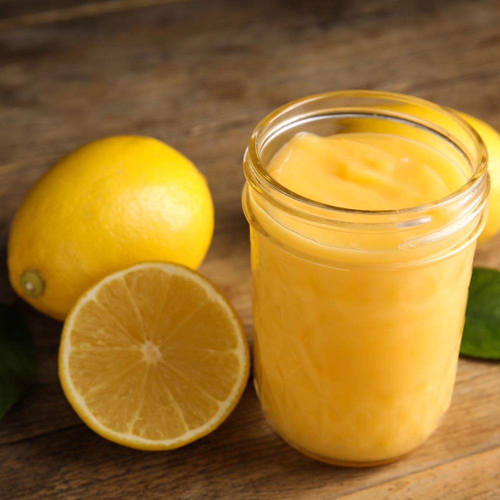 lemon curd in mason jar with cut lemon next to it